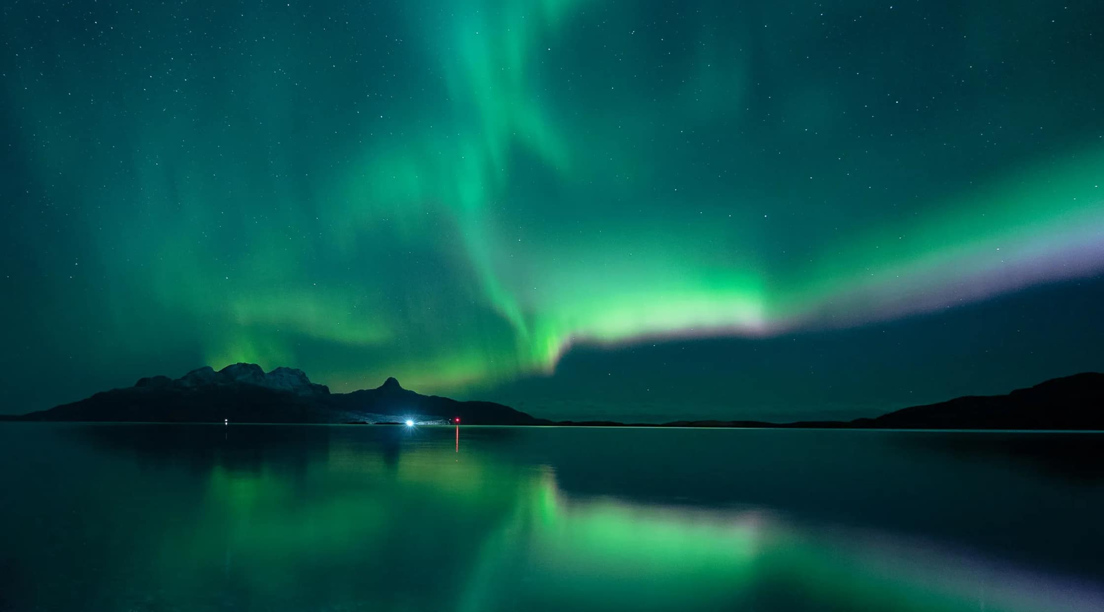 Nordlicht über einem Fjord, gespiegelt im Wasser