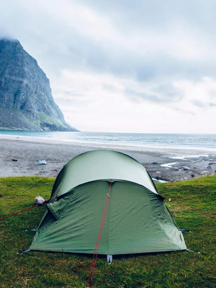 Green tent on the grass by a fjord