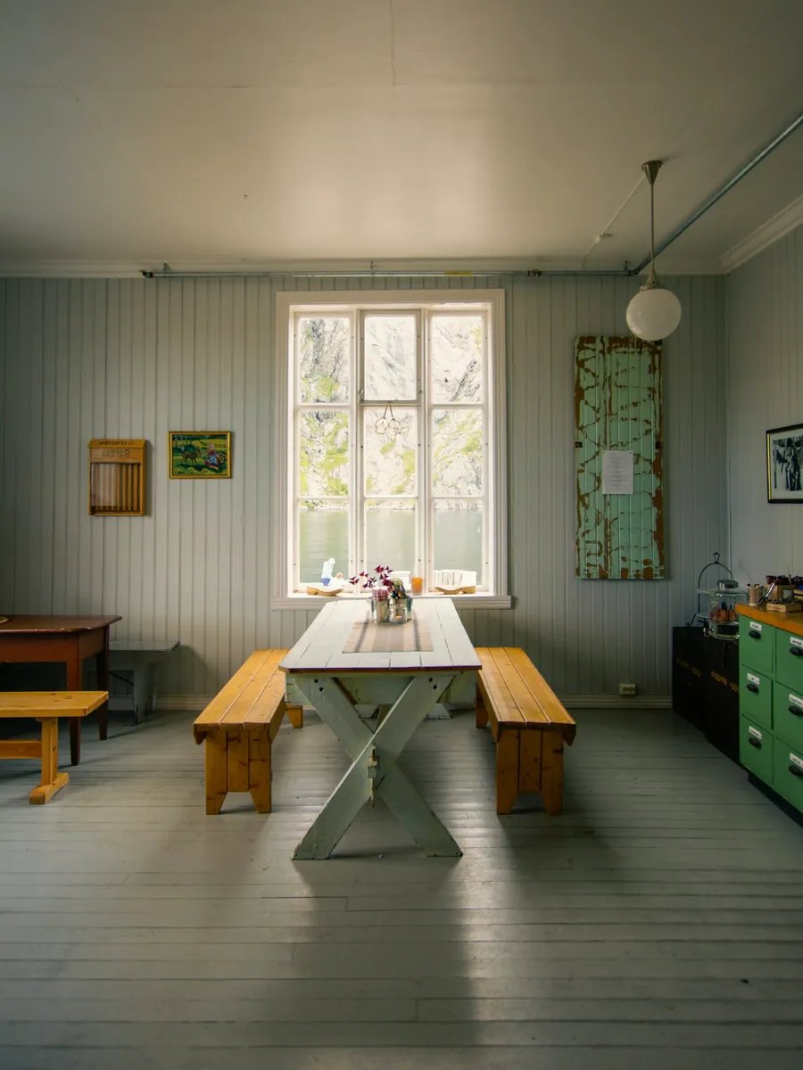 Simple dining room with a long table and benches by a window
