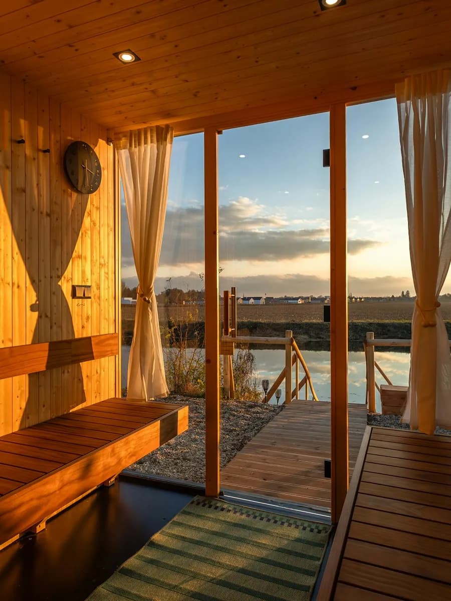 Sauna in light wood with a window facing the water at sunset